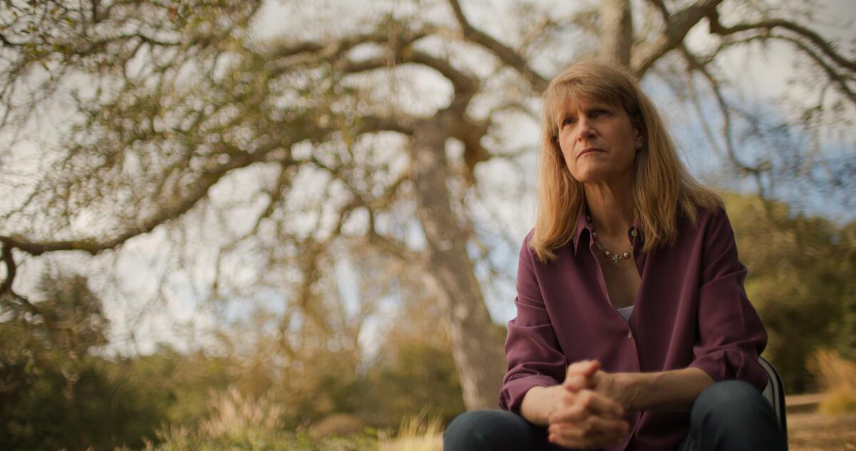 A woman in a purple cardigan sitting under a tree