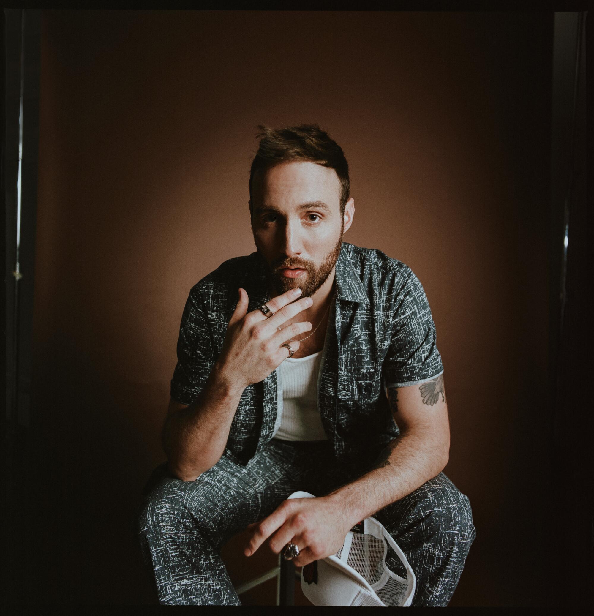 A male singer-songwriter sits for a photo