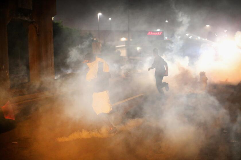 Tear gas fills the street in Ferguson, Mo., on Sunday evening. Blacks and whites differ sharply over whether the police response has "gone too far," a new poll shows.