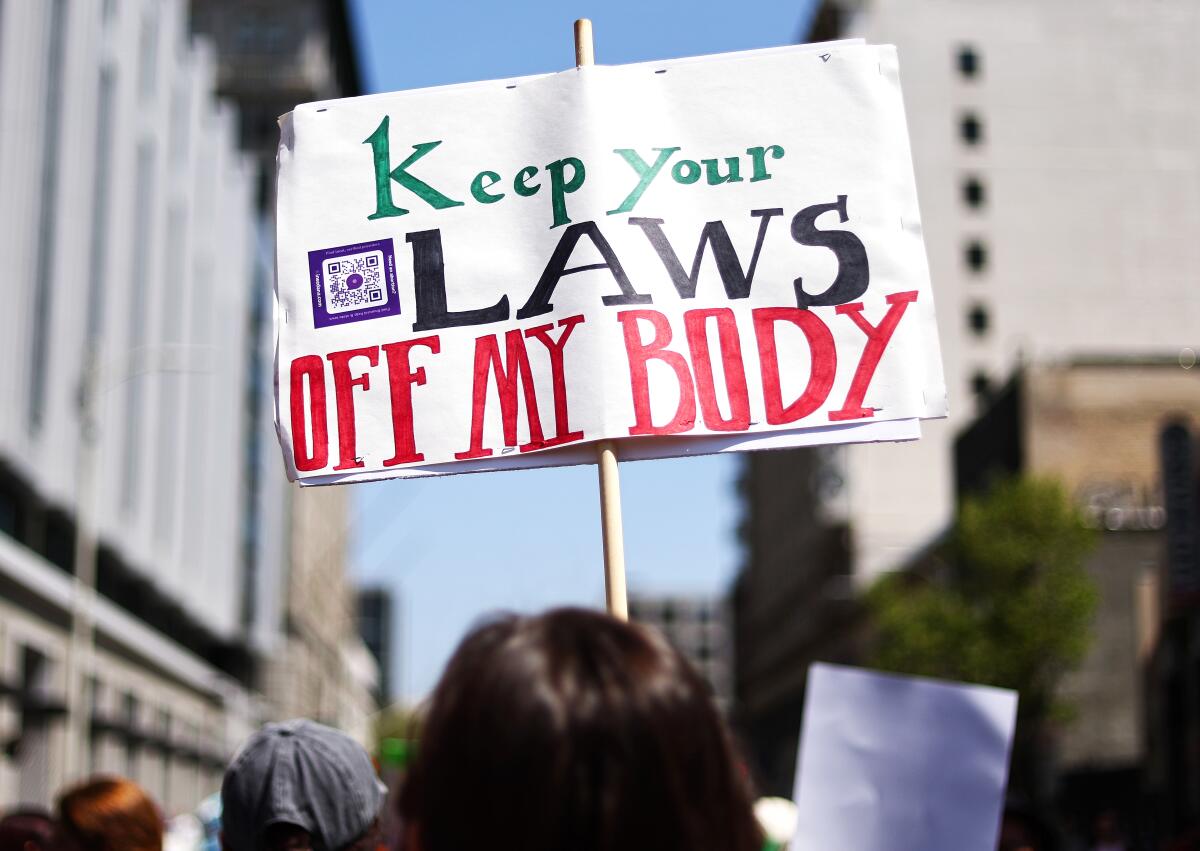A protester holding up a sign reading 'Keep Your Laws Off My Body'