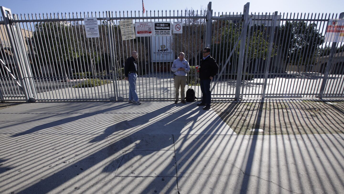 Ben Gertner, principal of Theodore Roosevelt High School, center; Jose Espinoza, right, principal of Math, Science, Technology Magnet Academy; and a volunteer stand outside locked school gates on Dec. 15.