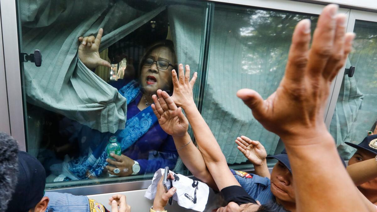Philippine Sen. Leila De Lima gestures to supporters from inside a police bus after her arraignment March 13 at a metropolitan trial court in Quezon City, east of Manila.