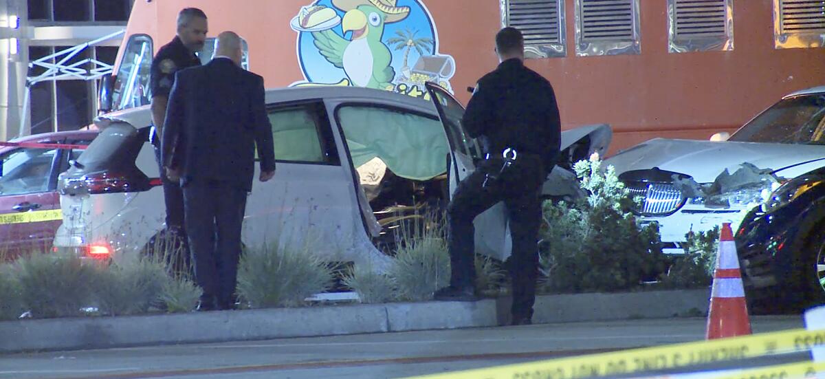Police officers examine the scene of a car crash.

