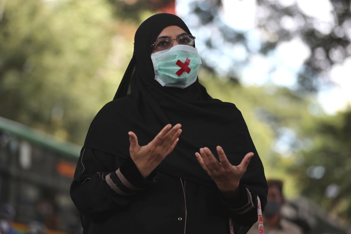 An Indian woman wearing a face mask as a precaution against the coronavirus speaks during a protest condemning the alleged gang rape and killing of a Dalit woman, in Bengaluru, India, Sunday, Oct. 4, 2020. India is the second worst-nation in terms of confirmed coronavirus caseload with 6.5 million cases. More than 100,000 people have died because of COVID-19. (AP Photo/Aijaz Rahi)