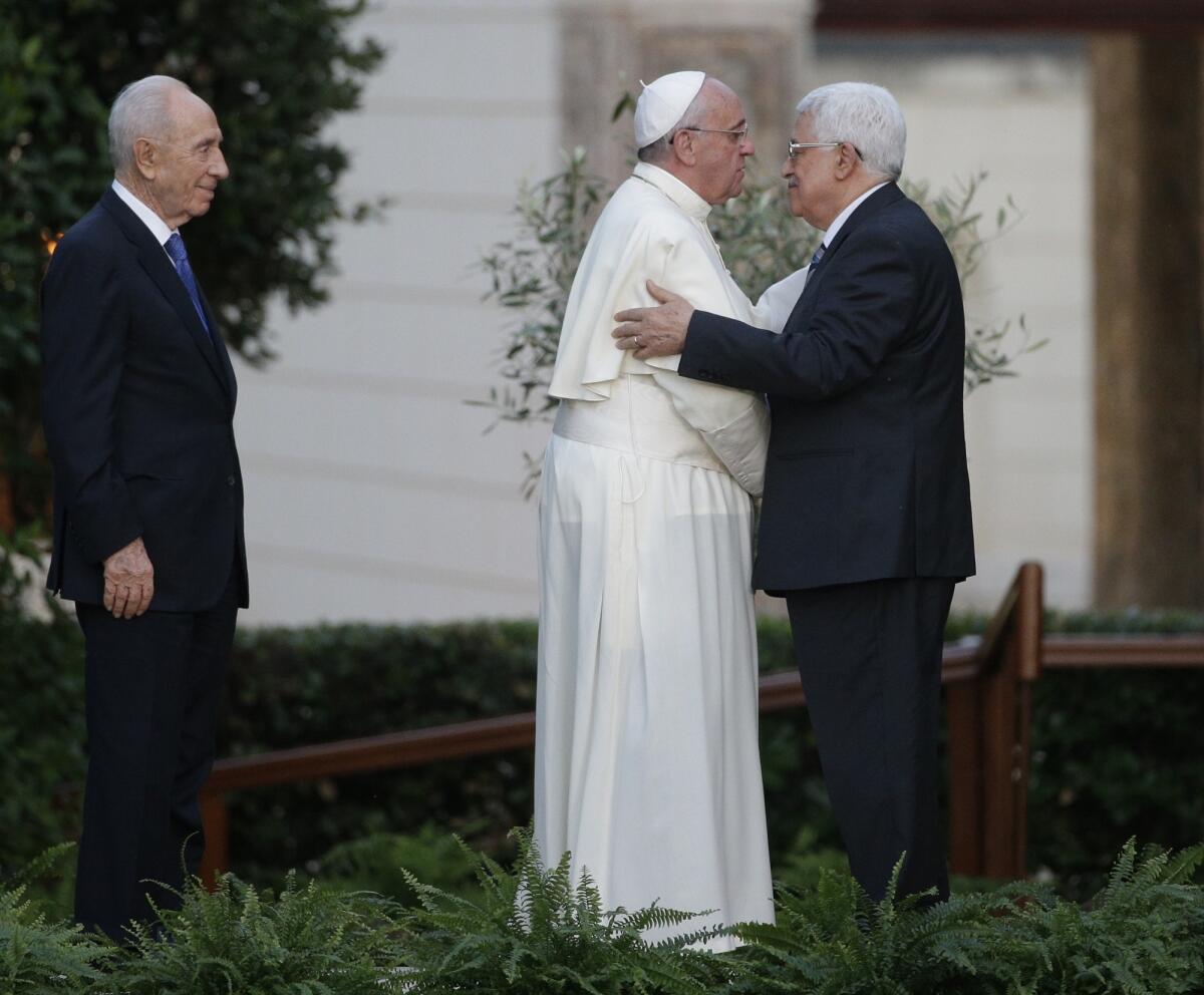 Pope Francis and Palestinian Authority President Mahmoud Abbas embrace last year at the Vatican. Israel's President Shimon Peres is at left.