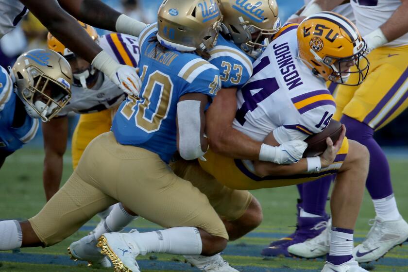 PASADENA, CALIF. - SEP. 4, 2021. UCLA linebacker Bo Calvert brings LSU quarterback Max Johnson down for a loss in the first quarter in the Rose Bowl on Saturday, Sept. 1, 2021. (Luis Sinco / Los Angeles Times)