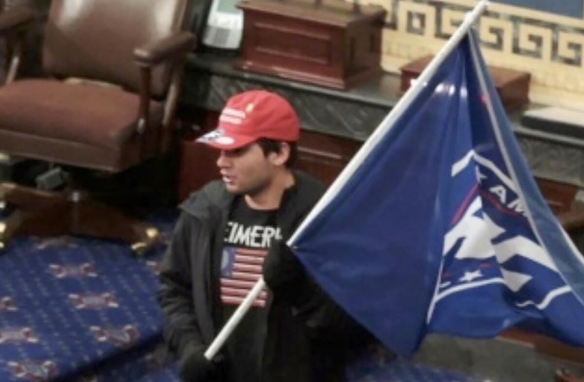 A man in a video still holds a flag in the Senate chambers