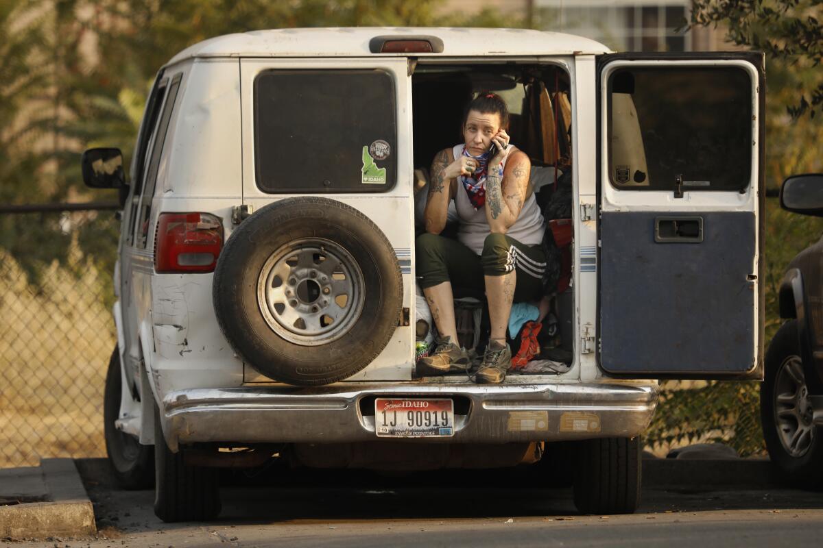 A woman sits in the back of her van in the parking lot of a motel