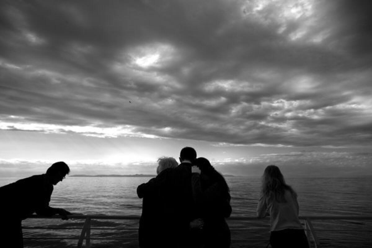 LONG BEACH, CA - DECEMBER 17, 2011 -- Clint McKinney, center, hugs his mother and wife after scattering the ashes of his father, Bill, who died of cancer, and brother, Byron, who died of prescription drug-related causes. ( Liz O. Baylen / Los Angeles Times)