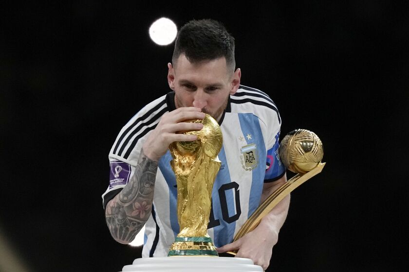 Argentina's Lionel Messi kisses the trophy after winning the World Cup final against France