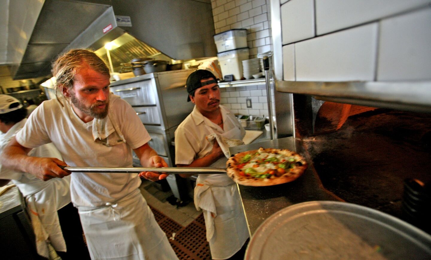 Gjelina chef Travis Lett pulls a pizza from the oven.