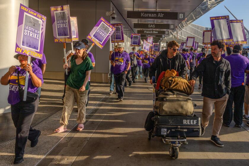 LOS ANGELES, CA - AUGUST 08: Passengers on the way to departing terminal negotiate through scores of Los Angeles city workers picketing on Tuesday, August 8, 2023, at LAX in Los Angeles, CA. (Irfan Khan / Los Angeles Times)