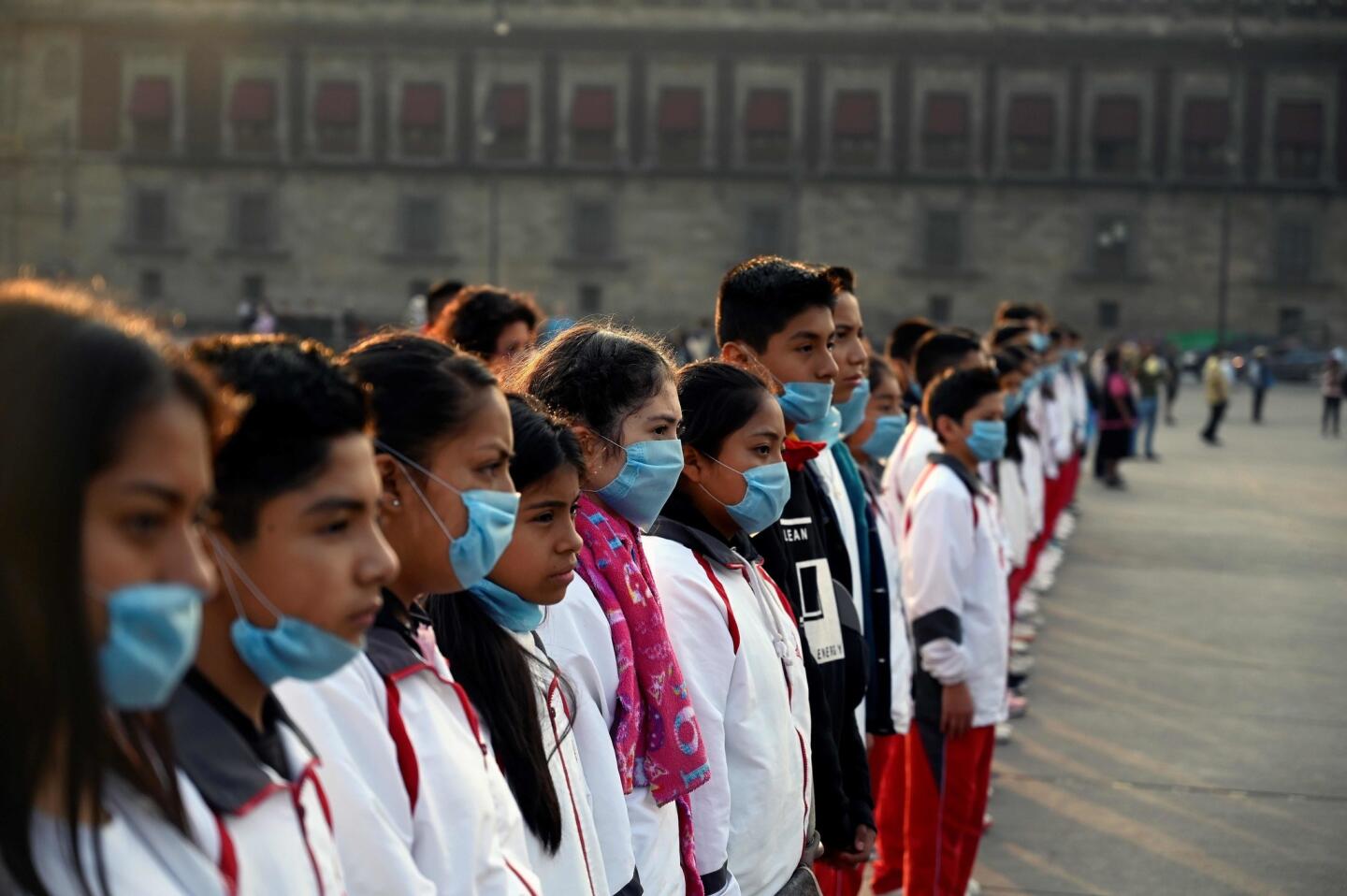 Children wear face masks while participating in a cultural event on Mexico City's central square, or Zocalo. A smoky haze that has blanketed the capital for the past week is fraying nerves, spurring health worries and generating criticism of elected officials.