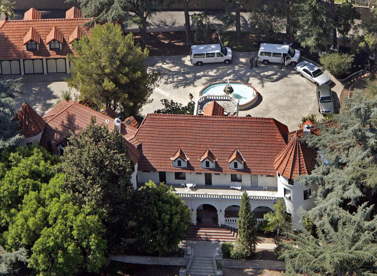 An aerial shot of a large castle-like home with a fountain in front