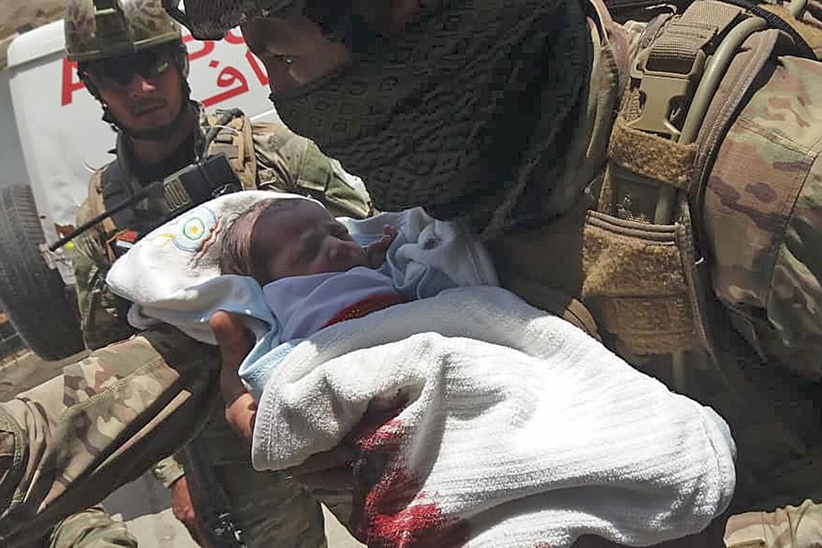 An Afghan security official carries a newborn baby from a hospital in the capital, Kabul,  after it was attacked May 12.