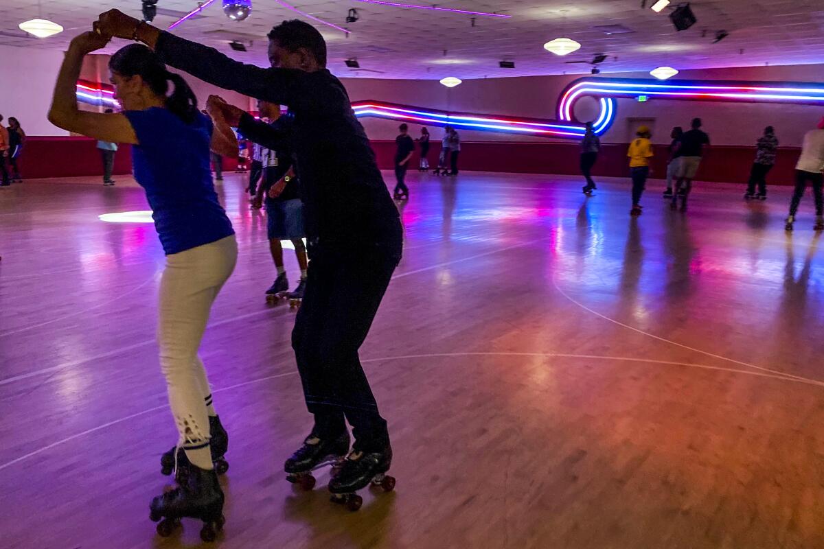 People roller skating at Fountain Valley Skate Center, with neon art on the wall
