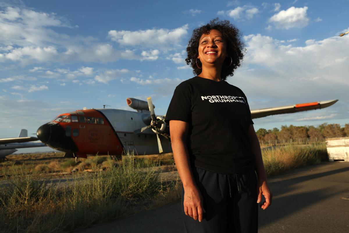 A woman smiles while standing near a plane