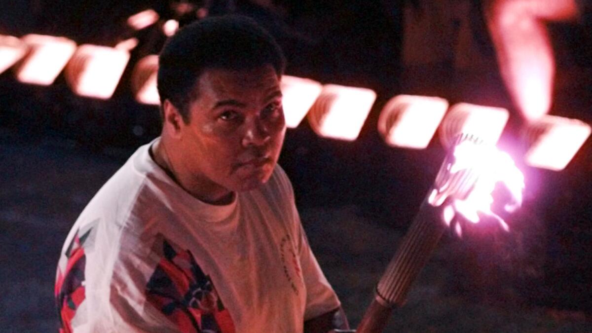 Muhammad Ali watches as the flame climbs up to the Olympic torch while taking part in the opening ceremonies of the 1996 Atlanta Olympic Games.