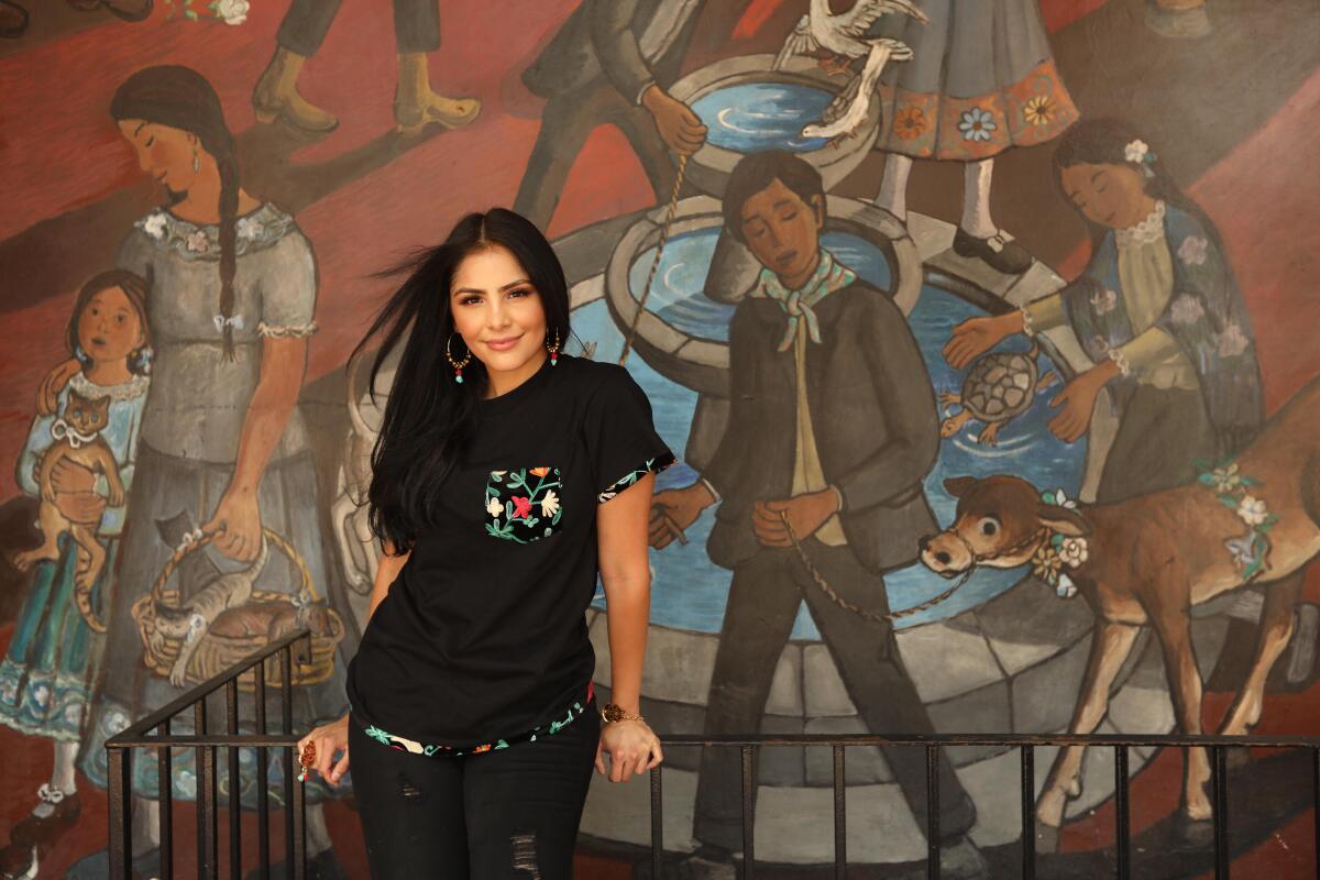 A woman stands at a railing in front of a colorful mural 