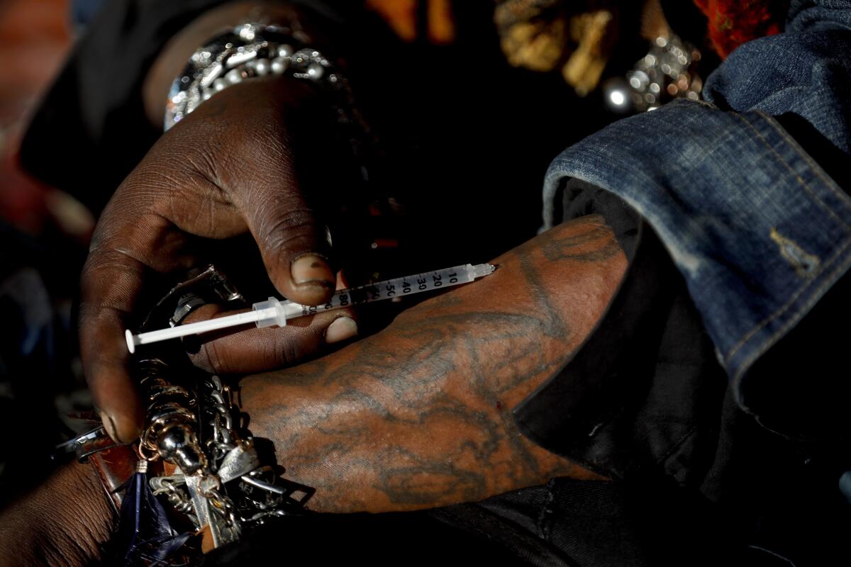While sitting on a sidewalk in Skid Row, Josua injects meth into his veins on Feb. 15, 2018.
