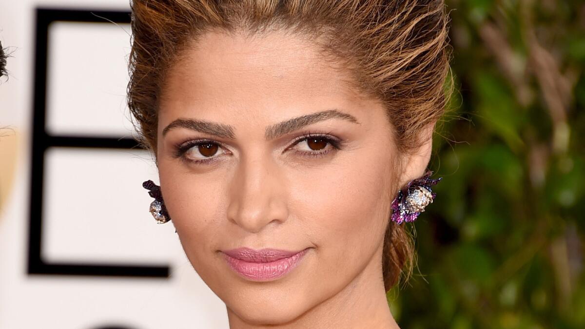 Model Camila Alves attends the 72nd Golden Globes wearing a pair of bright purple floral earrings.