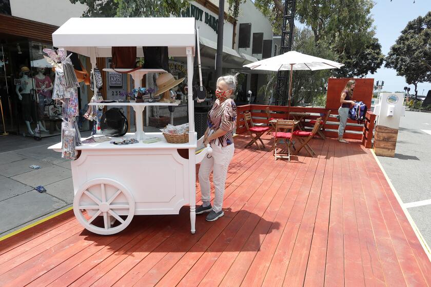 Violet Selleck of Violet Boutique store, rolls out a cart onto the new Promenade on Forest in downtown Laguna Beach, which opened to the public on Monday,