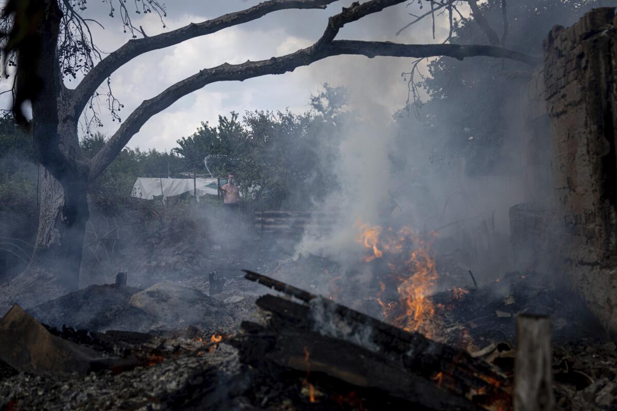 Un residente local (atrás) intenta combatir el fuego en la casa de un vecino,