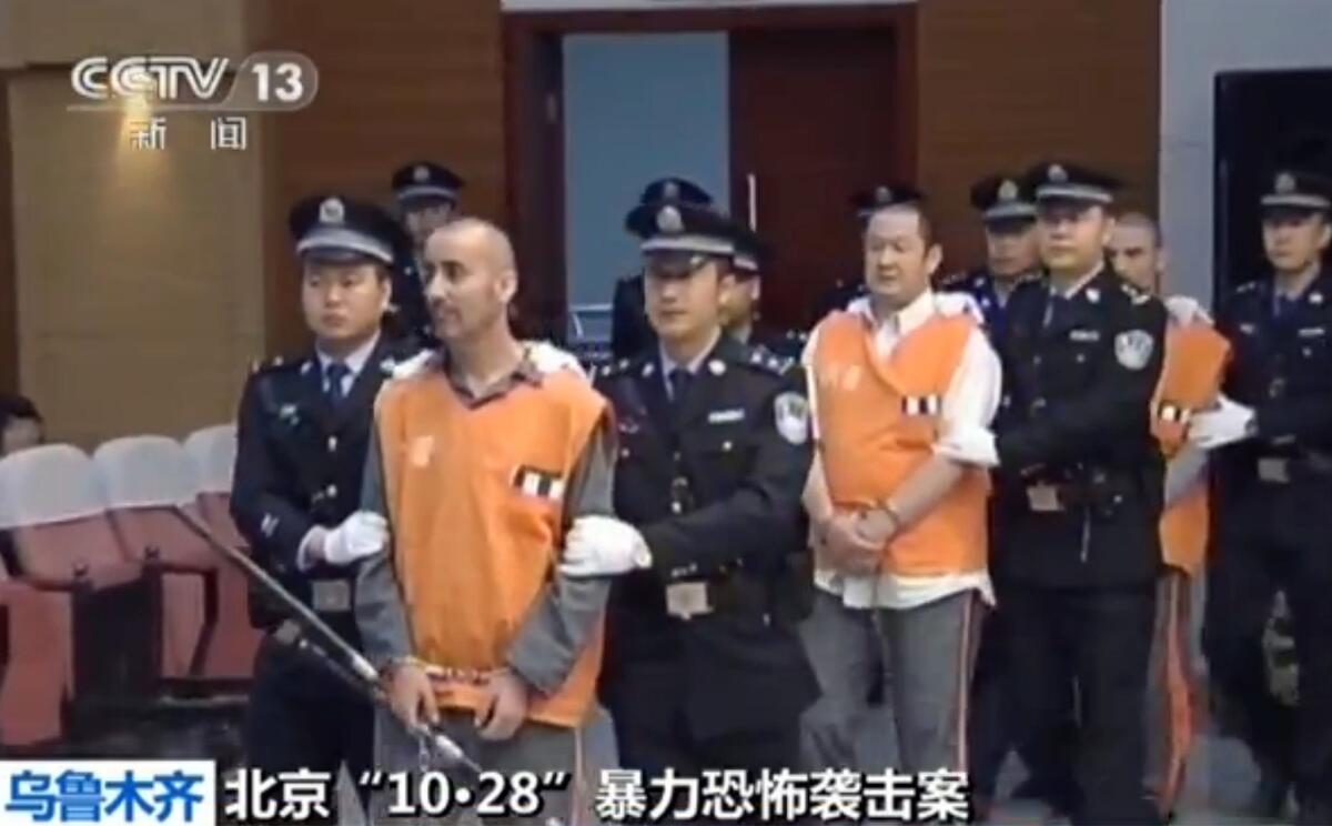 This screen grab taken from state broadcaster China Central Television on June 16 shows prisoners in orange being escorted into the Intermediate People's Court in the Xinjiang capital Urumqi for the trial of those accused of the attack in October 2013 in Beijing's Tiananmen Square that killed two tourists.