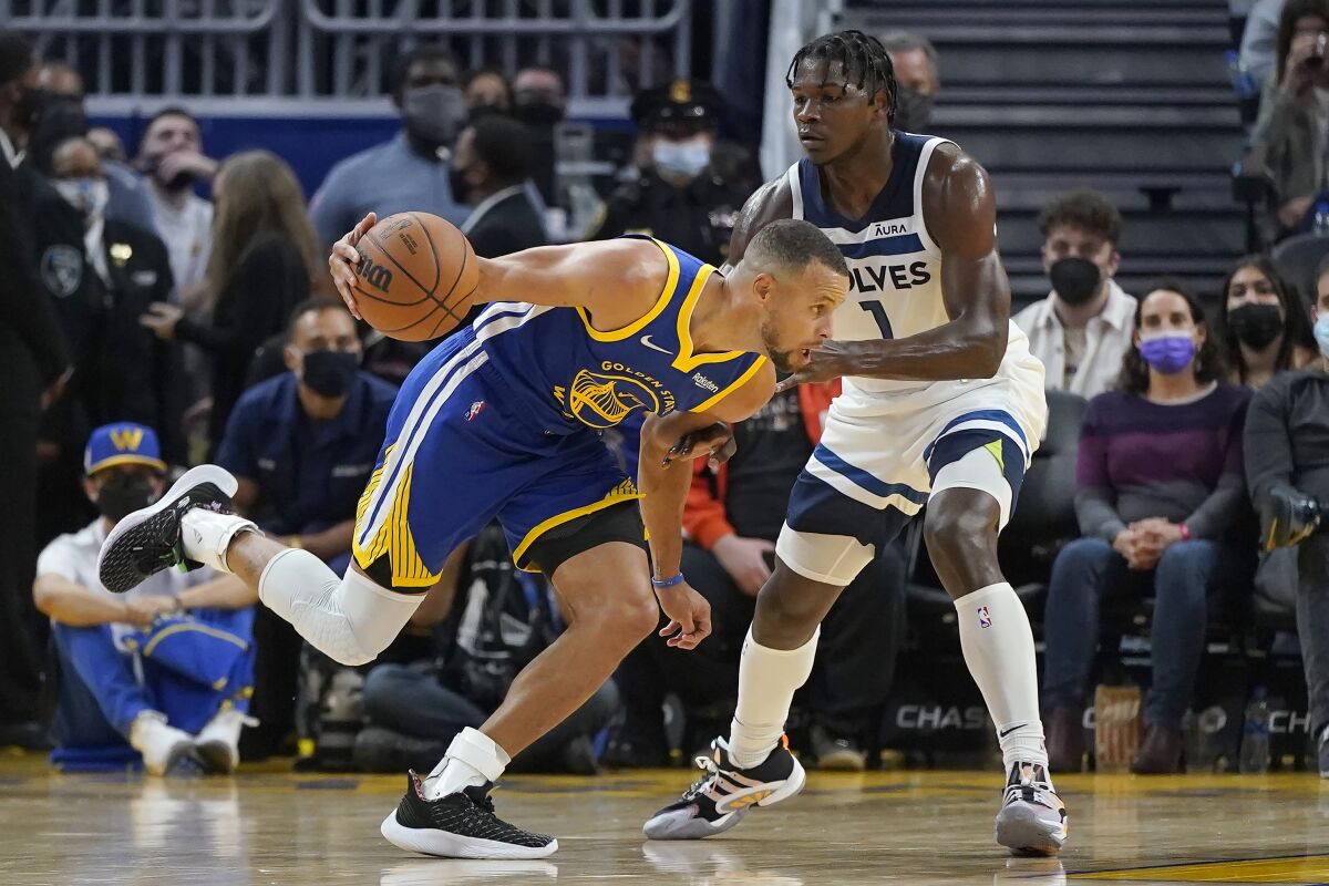 Golden State Warriors guard Stephen Curry, left, drives to the basket against Minnesota Timberwolves forward Anthony Edwards during the first half of an NBA basketball game in San Francisco, Wednesday, Nov. 10, 2021. (AP Photo/Jeff Chiu)