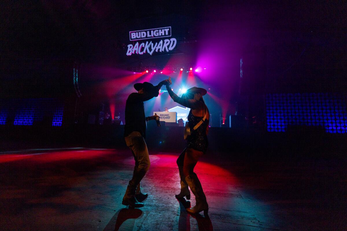 Силуэт пары, танцующей под вывеской с надписью Bud Light Backyard.