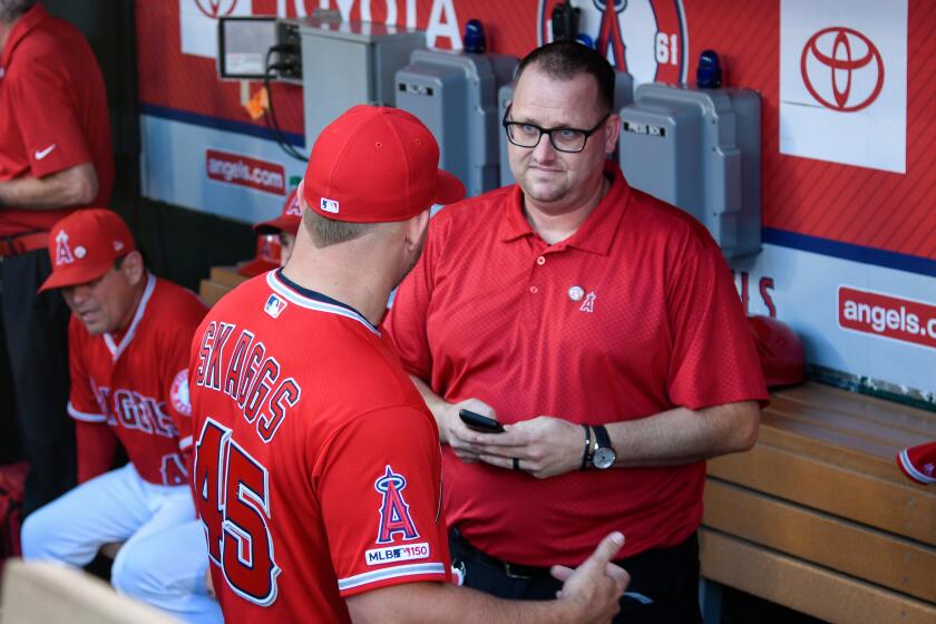 Mike Trout of the Los Angeles Angels speaks to Eric Kay in the dugout 