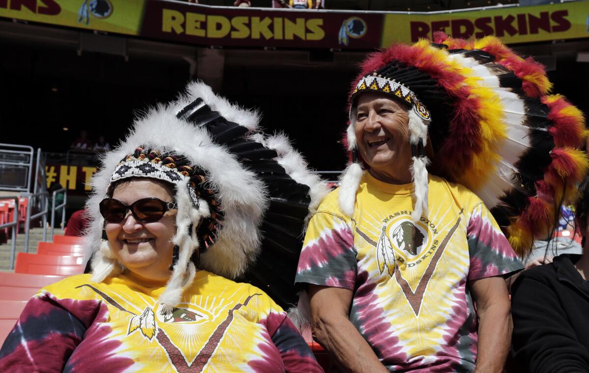 Washington fans Margaret DeWilde, left, and Carlos Rodriguez sit in the stands before a game against Jacksonville in Landover, Md.