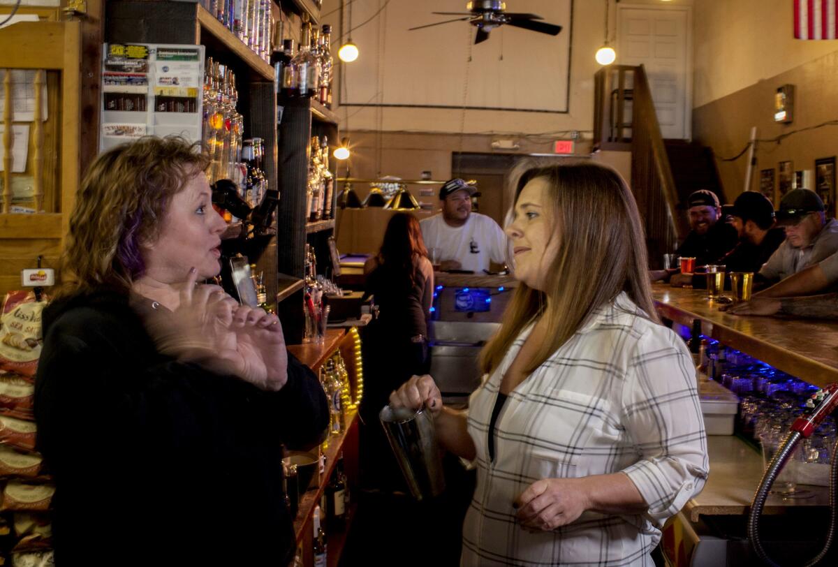 Mary Cox and Anna Louzon, owners of TJs Tavern, chat behind the bar in Vacaville, Calif..