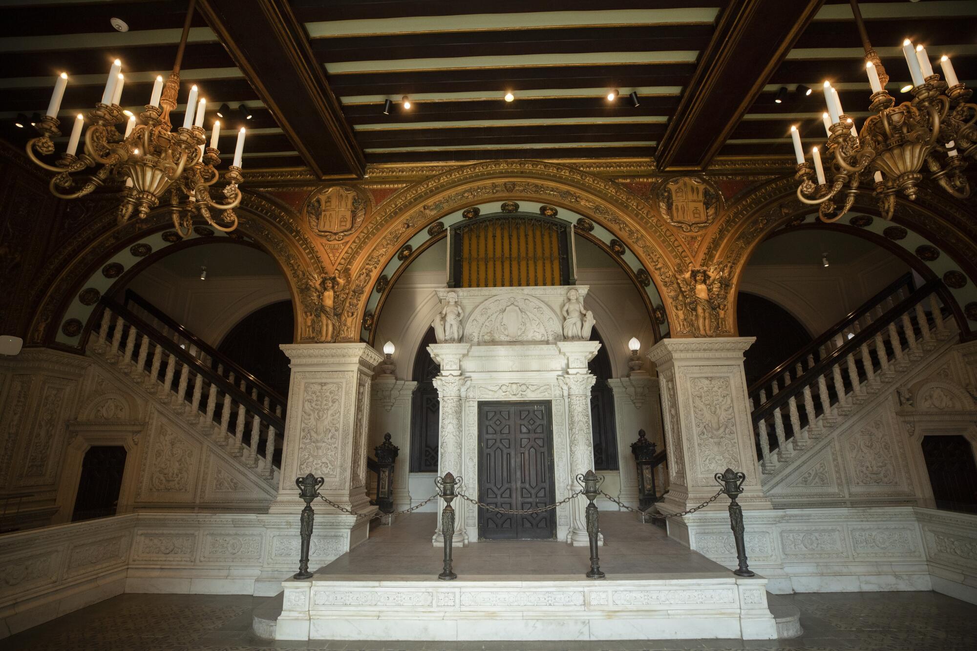 Daylight illuminates an ornate, baroque-style lobby that features a vintage elevator framed by marble columns