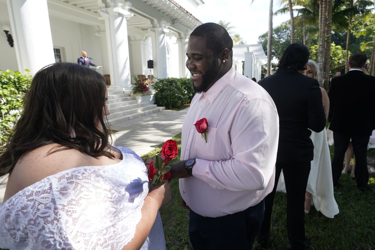 Sarah Horton, left, and Shackeem Frankson exchange rings as they get married during a Valentine's Day group wedding ceremony, Monday, Feb. 14, 2022, outside the Flagler Museum in Palm Beach, Fla. The pair were one of nine couples married by the Clerk of the Circuit Court & Comptroller for Palm Beach County during the annual event. (AP Photo/Wilfredo Lee)