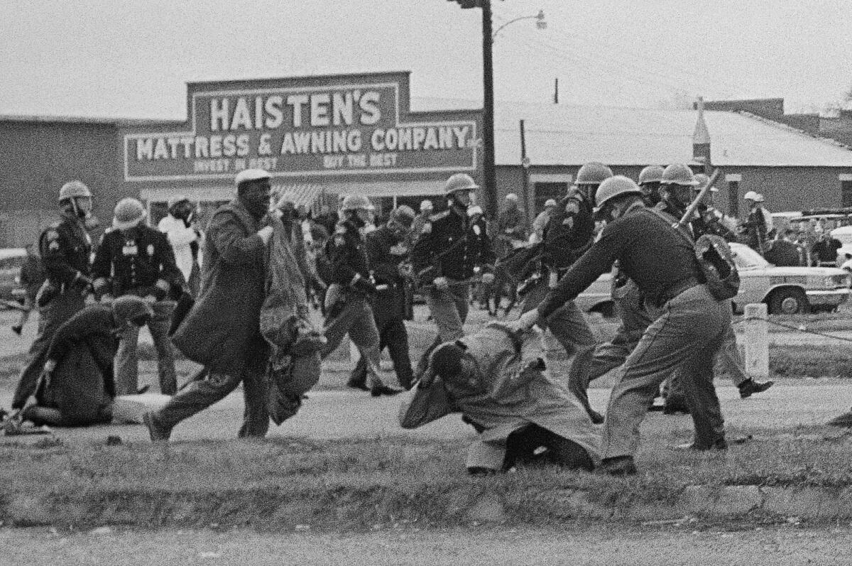 ARCHIVO - Un policía de Alabama golpea con un garrote a John Lewis, activista de derechos civiles, 