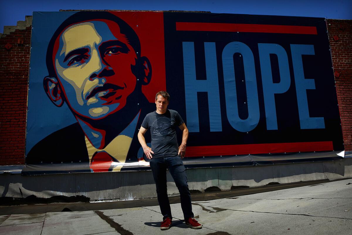 Shepard Fairey poses on a roof top in front of his "Hope" poster on July 2, 2008.