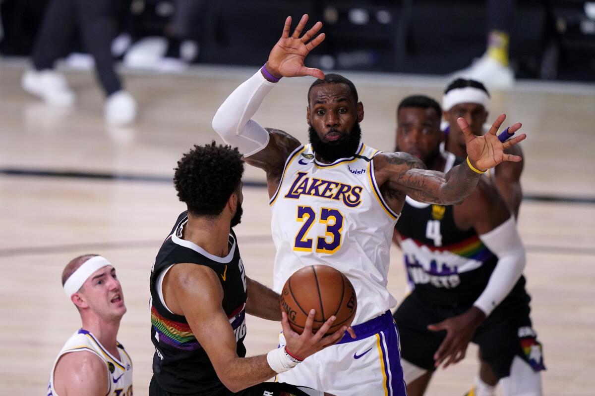 Lakers' LeBron James and Alex Caruso defend as Denver Nuggets guard Jamal Murray attempts to pass.