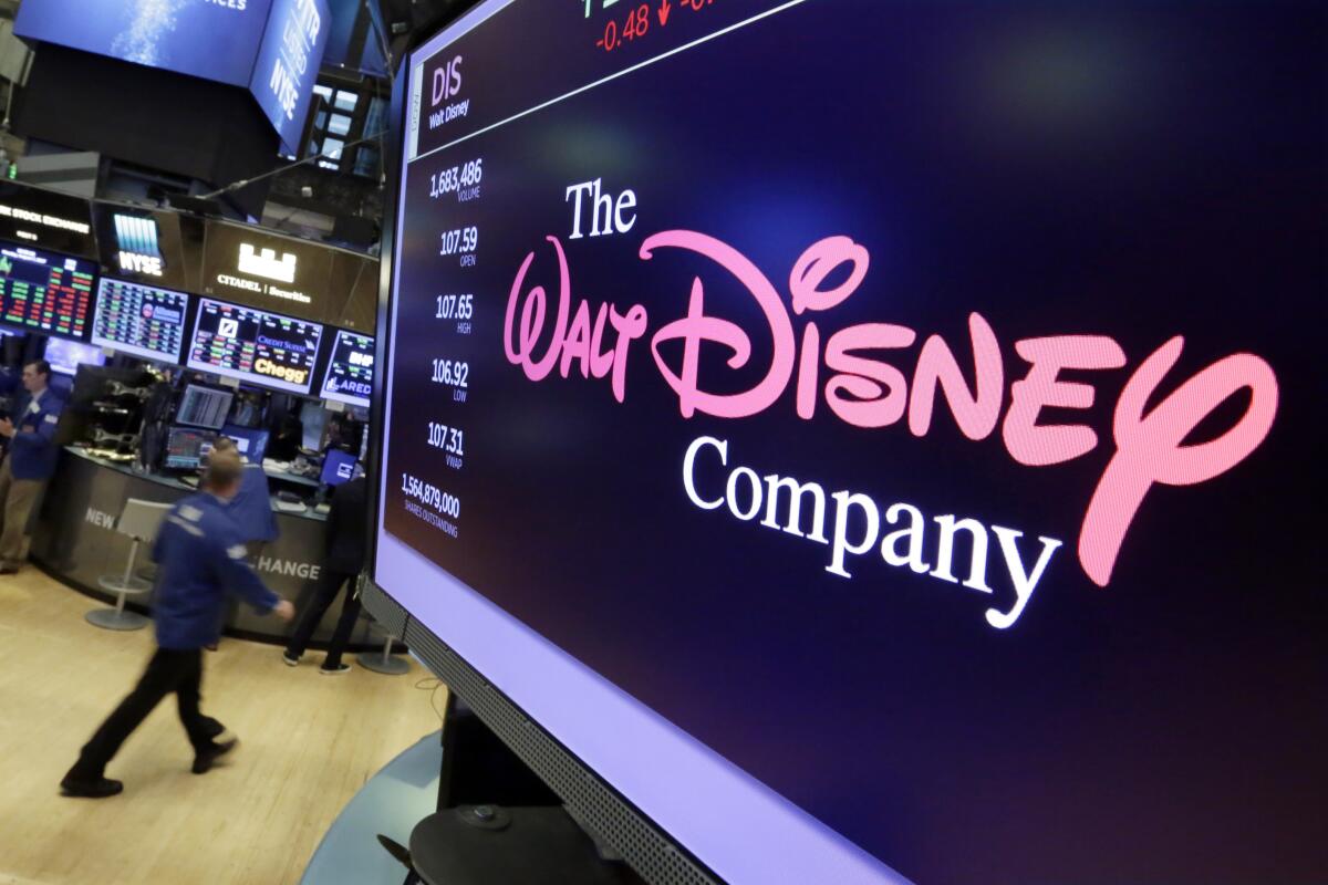 A pink-and-white logo for Walt Disney Co. appears on a screen in a room with other screens in the background.