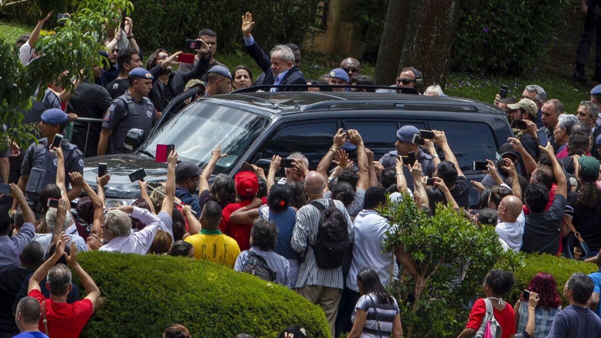 Brazilian former president Luiz Inacio Lula da Silva waves to supporters as he leaves the cemetery in Sao Paulo, Brazil, where he attended his grandson's funeral Saturday.