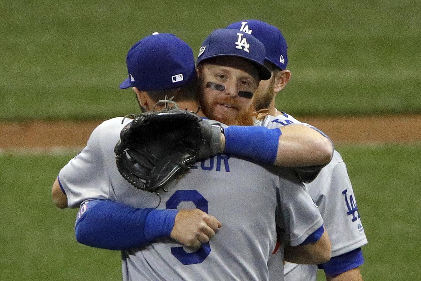 Los Angeles Dodgers' Justin Turner hugs Chris Taylor (3) after Game 2 of the National League Championship Series baseball game against the Milwaukee Brewers Saturday, Oct. 13, 2018, in Milwaukee. The Dodgers won 4-3. (AP Photo/Charlie Riedel)