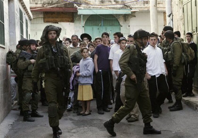Israeli soldiers guard Jewish settlers as they tour a Palestinian area in the Old City of the West Bank city of Hebron, Saturday, Nov. 22, 2008. Thousands of Jewish settlers converged on the divided West Bank city as part of a pilgrimage commemorating the death of the Matriarch Sarah, whom the Bible says was buried in Hebron. (AP Photo/Nasser Shiyoukhi)