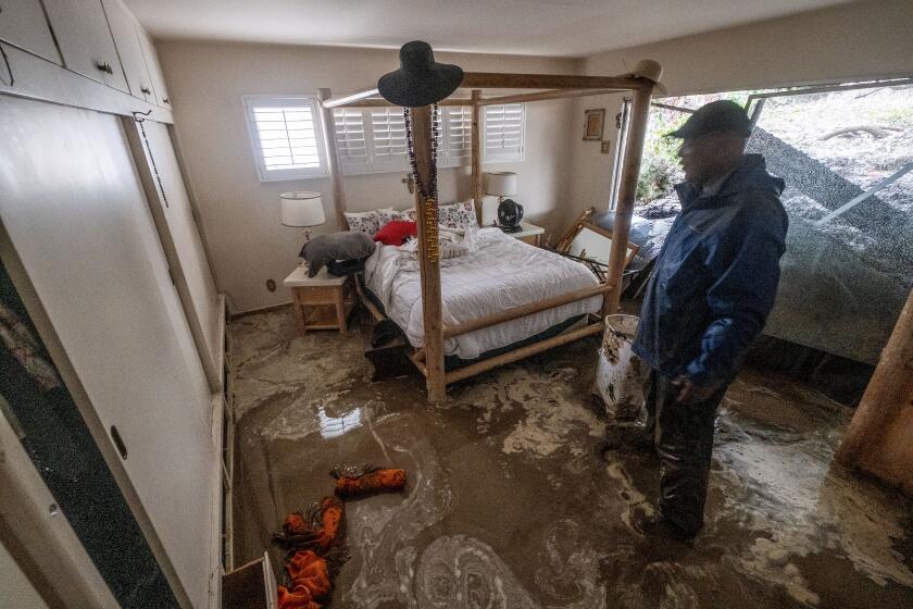 Los Angeles, CA - February 05: Blair Bowman, 65, friend of home owner watches as a home is damaged by a landslide during a rainstorm at Baldwin vista on Monday, Feb. 5, 2024 in Los Angeles, CA. (Ringo Chiu / For The Los Angeles Times)