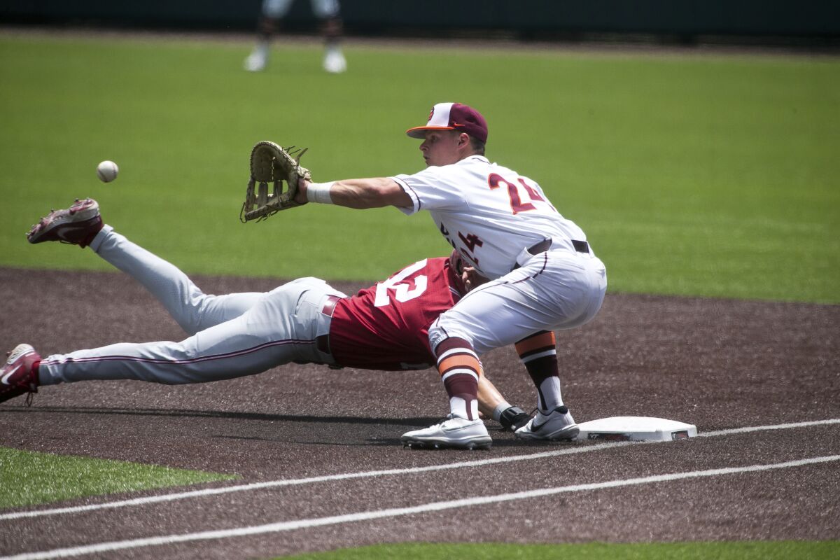Oklahoma's Brett Squires (12) beats the tag at first base from Virginia Tech's Nick Biddison (24) in the second inning of an NCAA college super regional baseball game Sunday, June 12, 2022, in Blacksburg, Va. (AP Photo/Scott P. Yates)