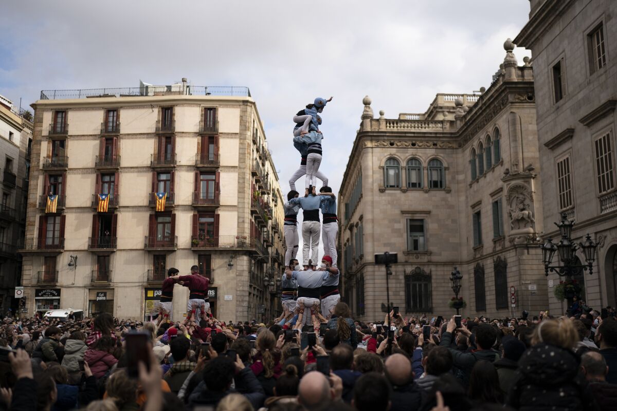 Members of the "Castellers de Poble Sec" complete their human tower during the Saint Eulàlia fesitivities in Barcelona, Spain, Friday, Feb. 11, 2022. After two years of canceled or muted celebrations due to the pandemic, this Mediterranean city went all-out to celebrate the feast, or “fest” in the Catalan language, of its patron. (AP Photo/Joan Mateu Parra)