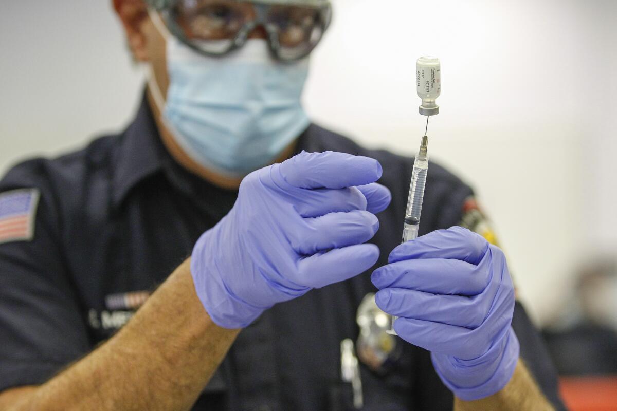 A Firefighter/paramedic prepares a Pfizer COVID-19 vaccine.