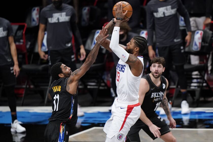 Brooklyn Nets guard Kyrie Irving (11) defends against Los Angeles Clippers guard Paul George (13) as Nets forward Joe Harris (12) watches during the second half of an NBA basketball game Tuesday, Feb. 2, 2021, in New York. (AP Photo/Kathy Willens)