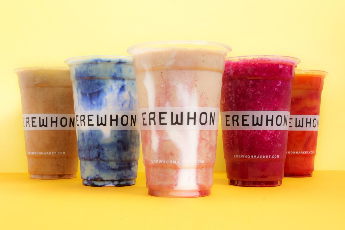 Five brightly colored drinks in plastic cups that bear the word "Erewhon."