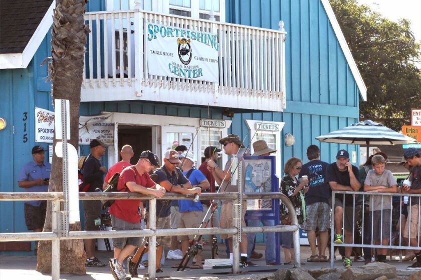 In front of Helgren's Sportfishing at the Oceanside Harbor people wait to board the Helgren's owned fishing boat named the Electra for a fishing excursion