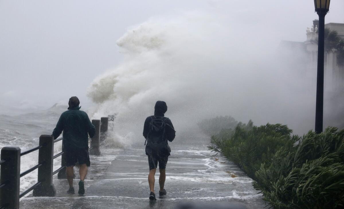 Pedestrians walk into huge waves crashing over the Battery park as Tropical Storm Irma hits Charleston, S.C., on Sept. 11, 2017.